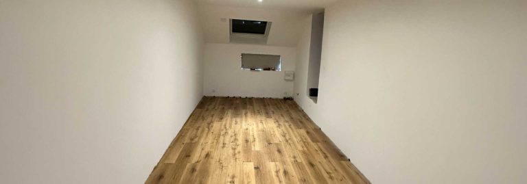 Combles aménagés avec un parquet stratifié et des murs lisses pour un espace moderne et lumineux