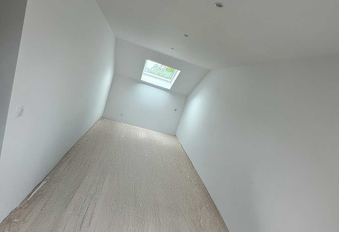 Aménagement de combles avec peinture blanche et Velux pour une luminosité optimale.